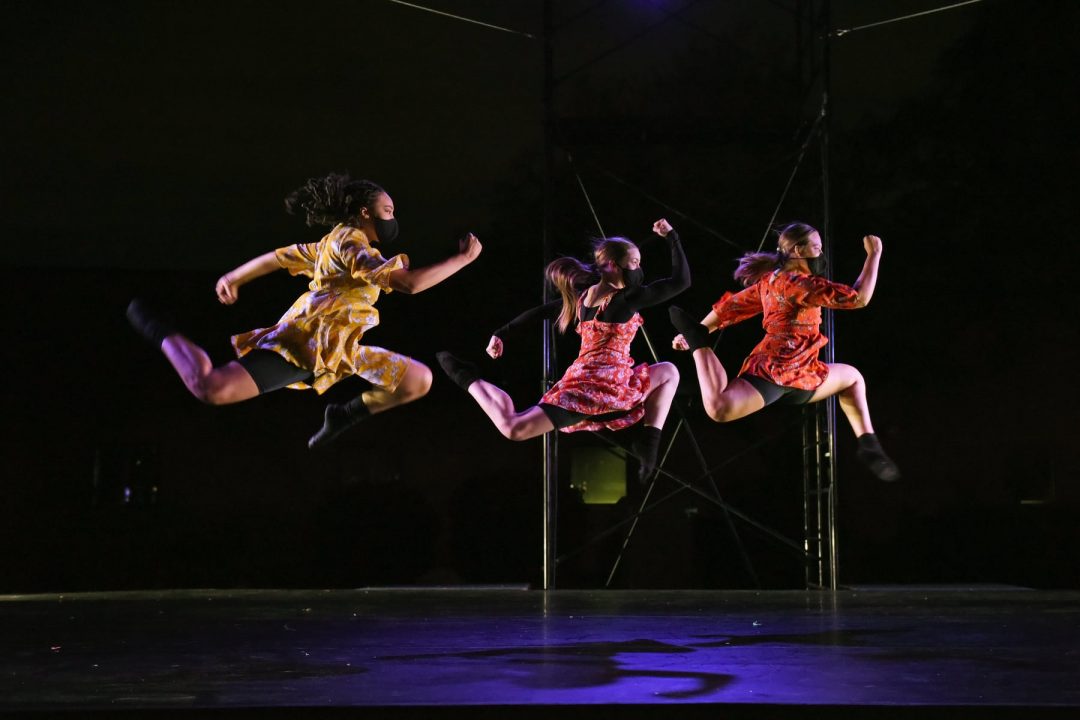 Three dancers of GCU's Ethington Dance Ensemble jumping in mid-air while performing choreography by Heather Beal